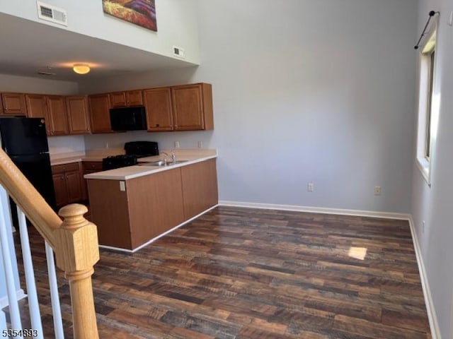 kitchen featuring visible vents, a peninsula, baseboards, light countertops, and black appliances