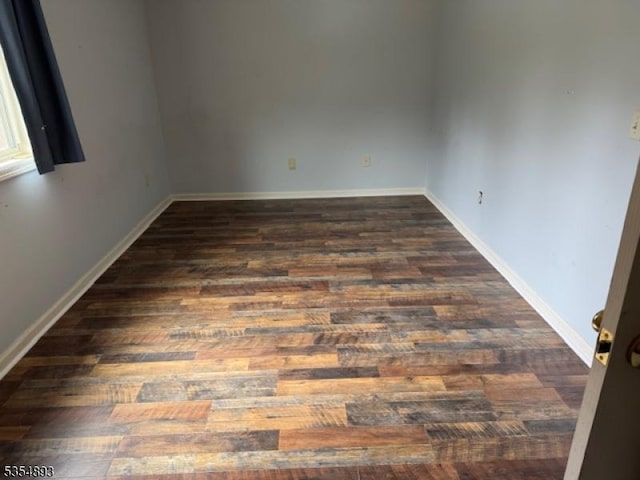 empty room with baseboards and dark wood-style flooring