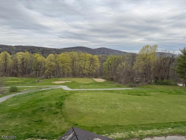 view of home's community with view of golf course, a mountain view, and a forest view
