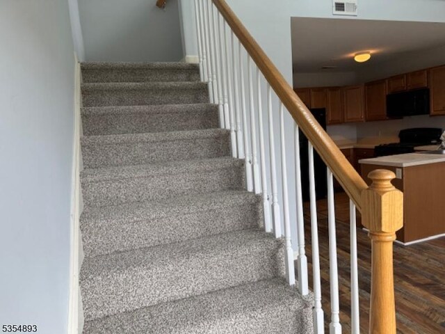 staircase with wood finished floors and visible vents