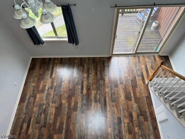 unfurnished dining area with an inviting chandelier, baseboards, stairs, and wood finished floors