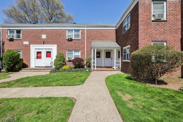 view of property featuring brick siding and a front yard