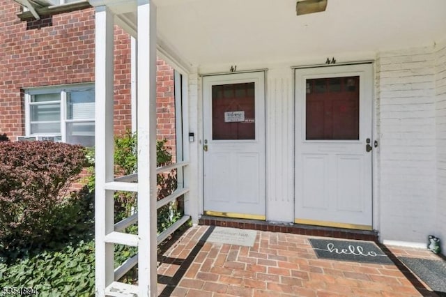 doorway to property with brick siding and covered porch
