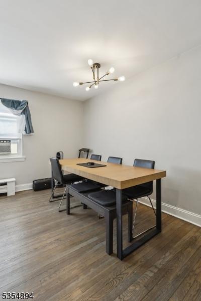 dining area featuring baseboards, cooling unit, a chandelier, and dark wood-style floors