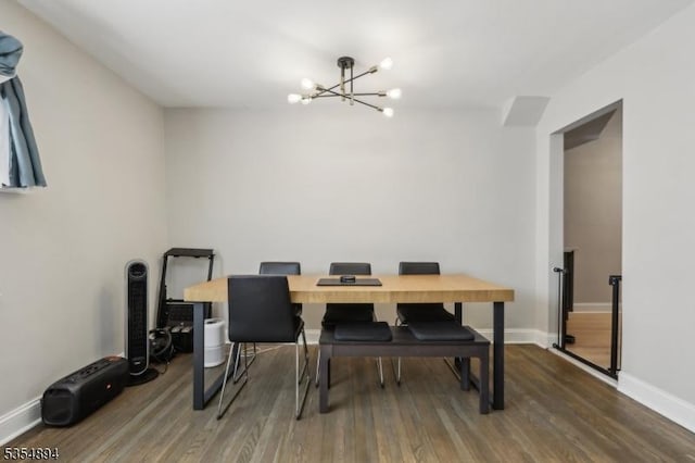 dining space featuring baseboards, wood finished floors, and a chandelier