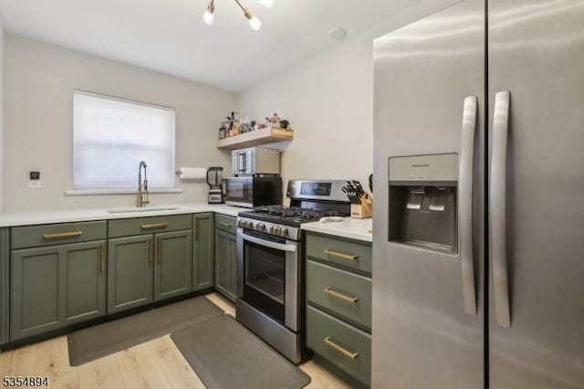 kitchen featuring light countertops, stainless steel appliances, green cabinetry, and a sink