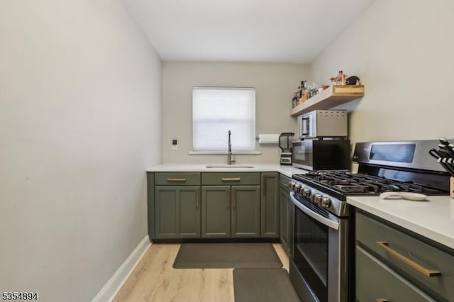 kitchen with open shelves, a sink, light wood-style flooring, green cabinets, and stainless steel appliances