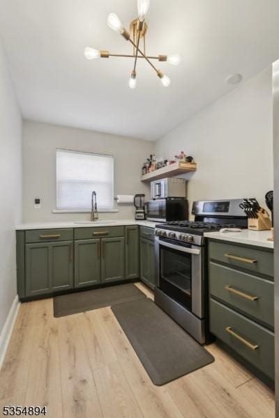 kitchen with appliances with stainless steel finishes, a sink, light countertops, a chandelier, and green cabinets