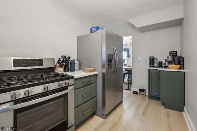 kitchen featuring light wood-style floors, appliances with stainless steel finishes, baseboards, and light countertops