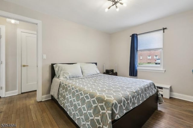 bedroom featuring baseboards, dark wood-style flooring, and an inviting chandelier