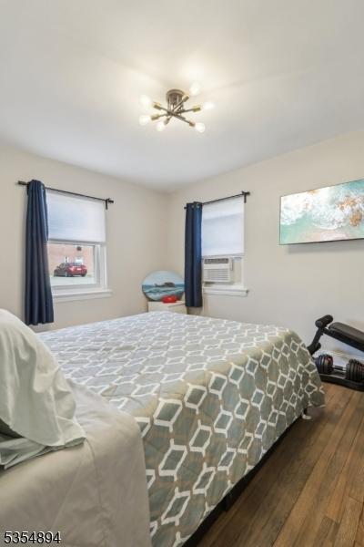 bedroom featuring cooling unit, wood finished floors, and a notable chandelier