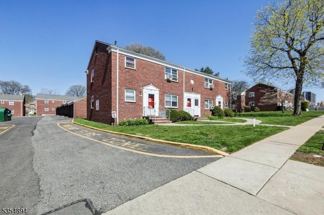 view of property with brick siding, a front lawn, and a residential view