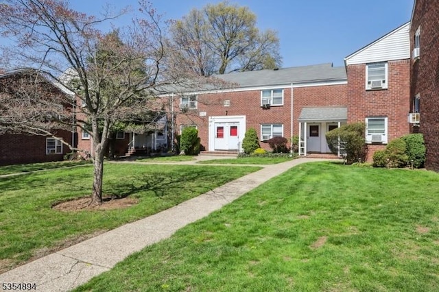view of property featuring brick siding, cooling unit, and a front yard