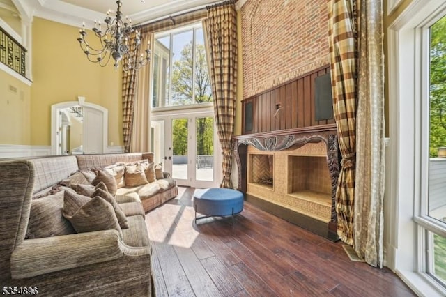 sitting room with ornamental molding, a towering ceiling, dark wood-style floors, french doors, and a notable chandelier