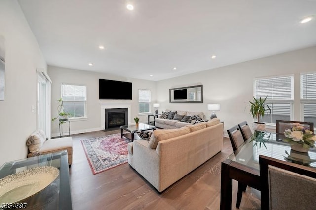 living room featuring a fireplace with flush hearth, recessed lighting, and wood finished floors