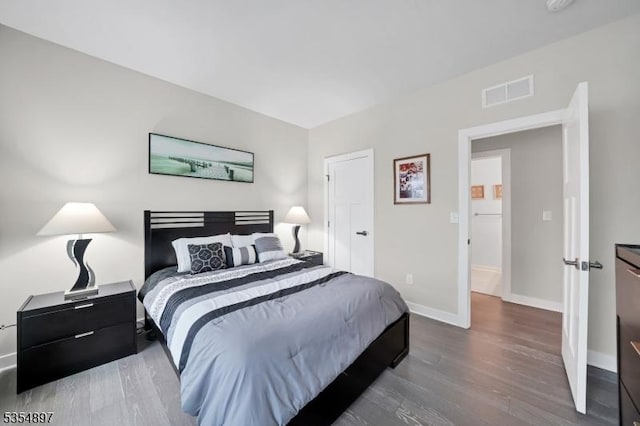 bedroom with baseboards, visible vents, and wood finished floors