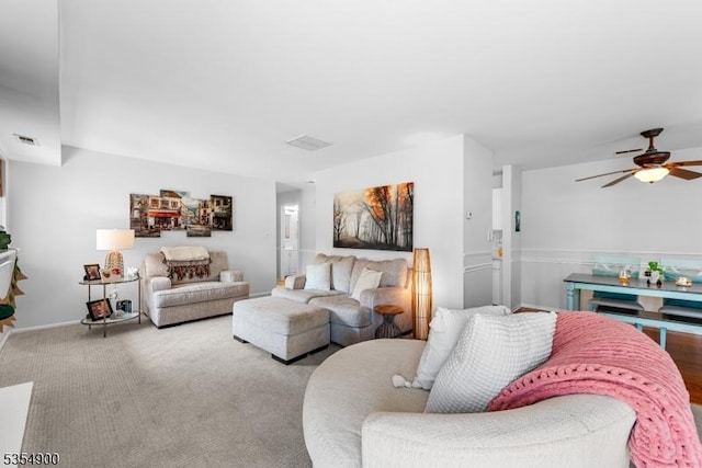 living room with a ceiling fan, visible vents, and carpet