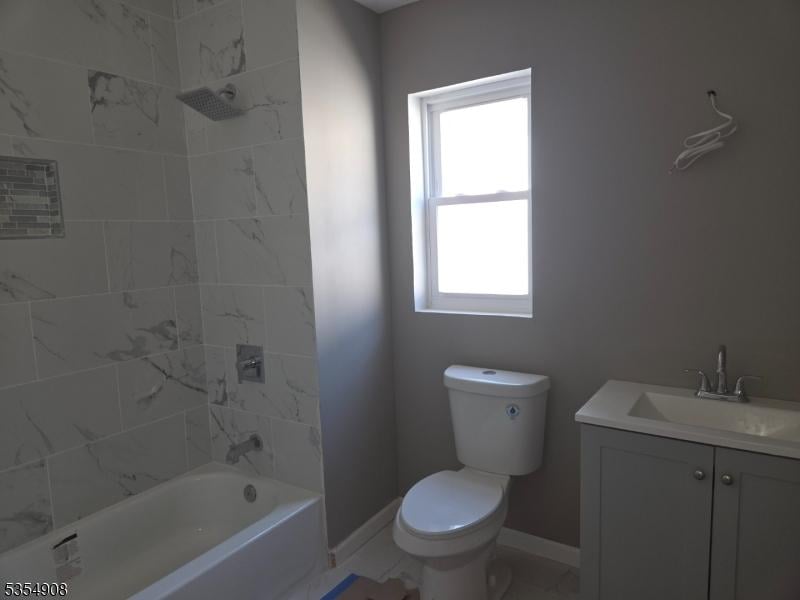 bathroom featuring toilet, baseboards, plenty of natural light, and vanity