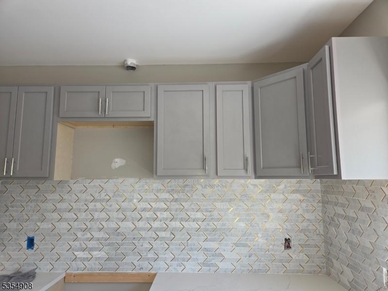 kitchen featuring light countertops, decorative backsplash, and gray cabinets