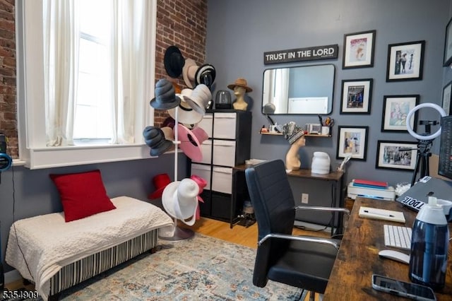 bedroom featuring brick wall and wood finished floors