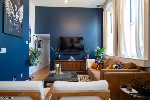 living area with baseboards, wood finished floors, and visible vents
