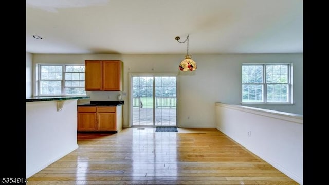 27 Suydam Rd, Franklin Twp, NJ 08873 - kitchen with dark countertops, light wood-type flooring, brown cabinetry, pendant lighting, and baseboards