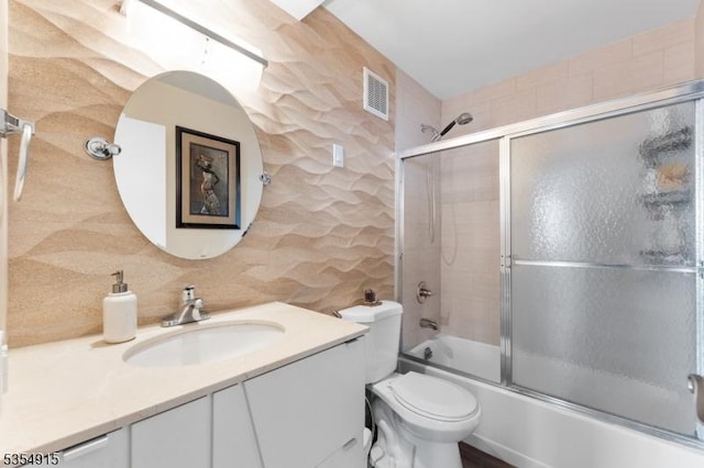 bathroom featuring visible vents, decorative backsplash, vanity, toilet, and bath / shower combo with glass door