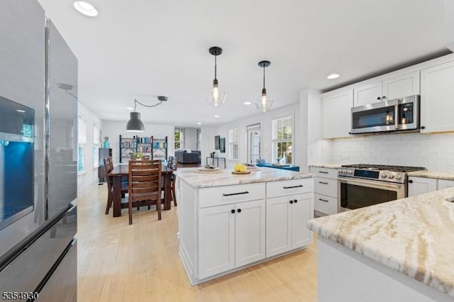 kitchen featuring appliances with stainless steel finishes, plenty of natural light, light wood-style flooring, recessed lighting, and pendant lighting