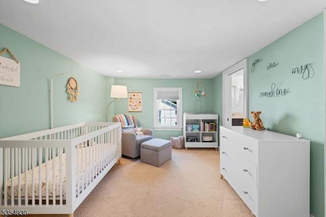 bedroom with a crib, light colored carpet, and recessed lighting