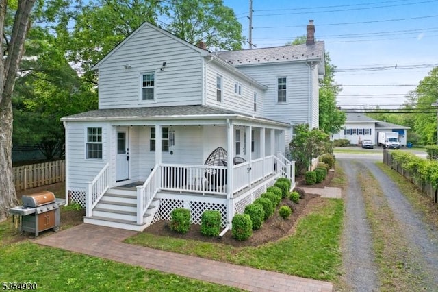 view of front of home with a porch, a chimney, and fence
