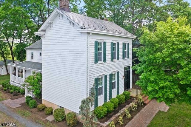 view of side of home featuring a chimney and view of wooded area
