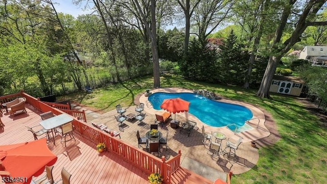 pool featuring a lawn, an outbuilding, a wooden deck, a storage unit, and outdoor dining space