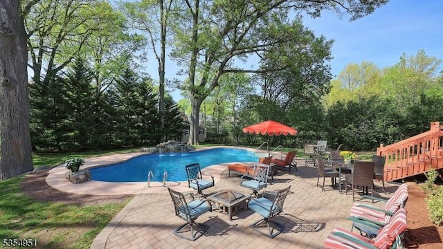 outdoor pool with a patio area and an outdoor fire pit