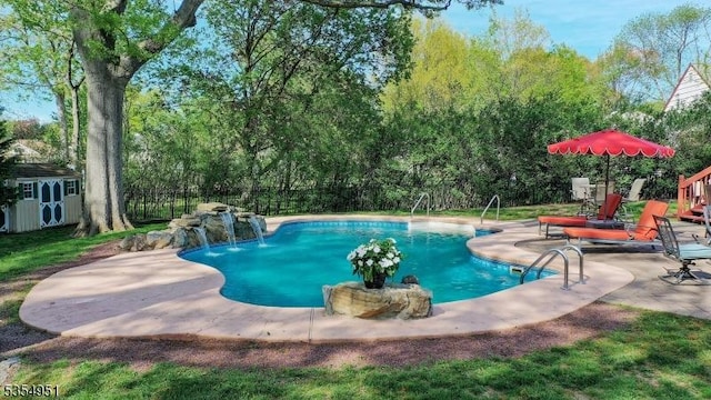 view of pool featuring a patio, a fenced backyard, a shed, a fenced in pool, and an outbuilding