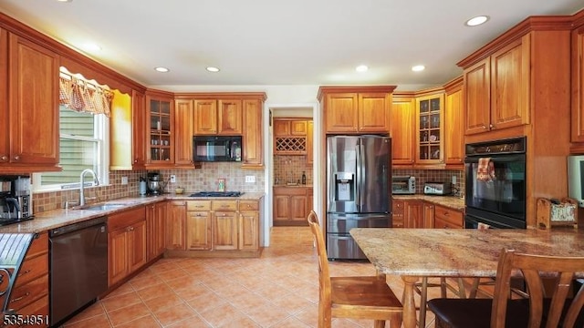 kitchen with brown cabinets, a sink, light tile patterned floors, black appliances, and recessed lighting