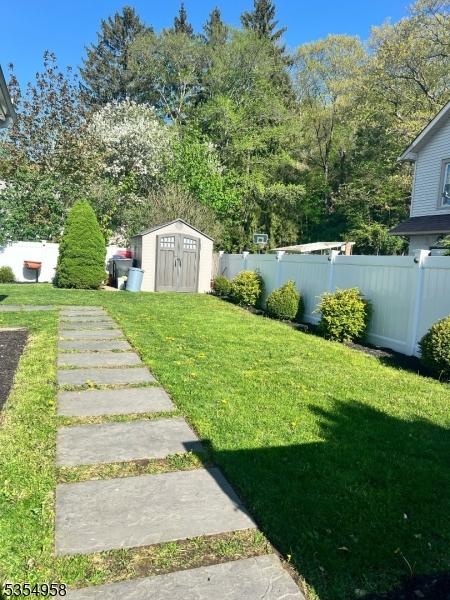 view of yard featuring a storage shed, fence, and an outbuilding