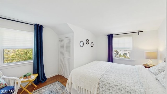 bedroom with a closet, baseboards, vaulted ceiling, and wood finished floors