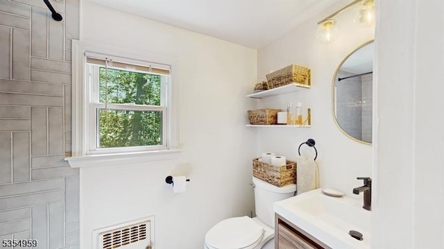 bathroom featuring heating unit, vanity, and toilet