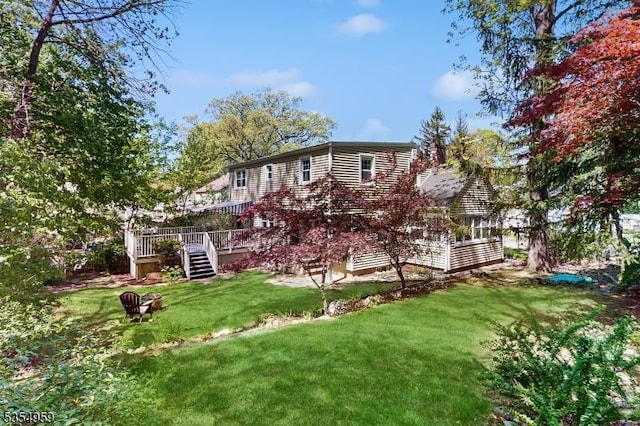 rear view of property featuring a yard, a deck, and stairway