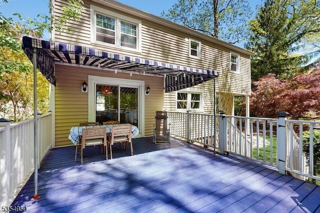 rear view of property with a deck and outdoor dining space