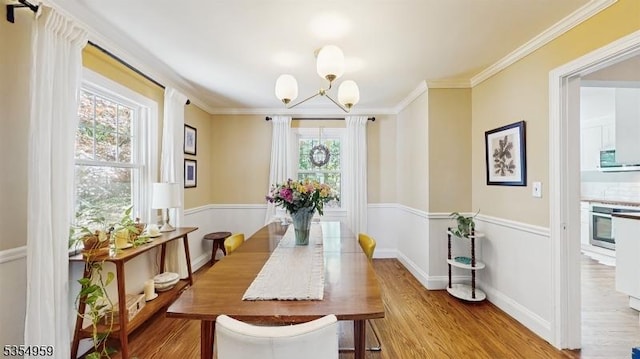 dining space with crown molding, wood finished floors, and a notable chandelier