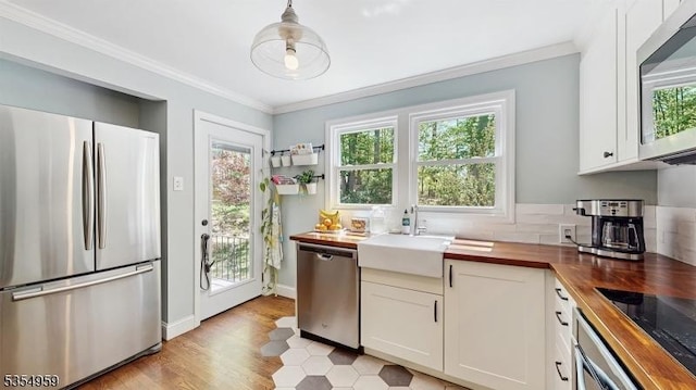 kitchen featuring a sink, wooden counters, stainless steel appliances, and a healthy amount of sunlight