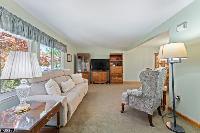 living room featuring baseboards, vaulted ceiling, and light colored carpet