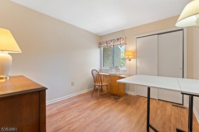 office area with baseboards, visible vents, and light wood-style flooring
