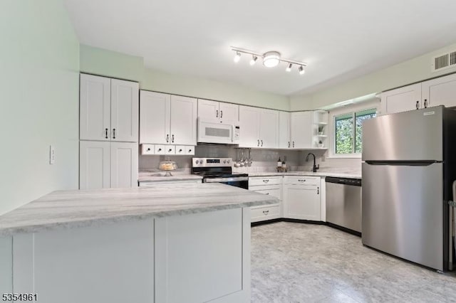 kitchen featuring white cabinets, open shelves, appliances with stainless steel finishes, a sink, and visible vents