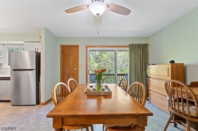 dining room featuring baseboards, ceiling fan, and light carpet