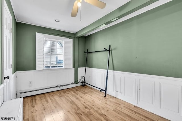 123 Robbinwood Ter, Linden City, NJ 07036 - unfurnished bedroom featuring a baseboard heating unit, a wainscoted wall, wood finished floors, and a ceiling fan