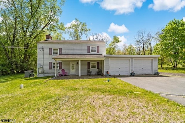 traditional-style home with an attached garage, a front yard, a chimney, covered porch, and driveway