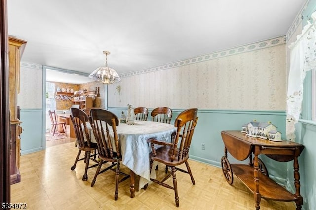 dining space with light floors, wallpapered walls, and a notable chandelier