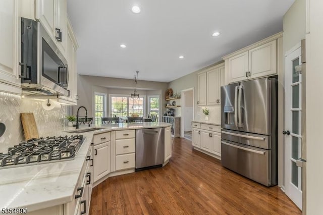 kitchen with a peninsula, tasteful backsplash, dark wood finished floors, recessed lighting, and appliances with stainless steel finishes